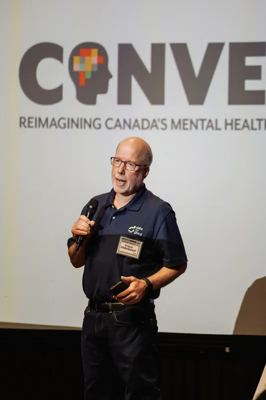 A presenter speaks beneath the CONVERGE mental health initiative logo.