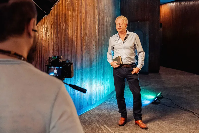 A photographer captures a guest portrait against a blue-lit wall.
