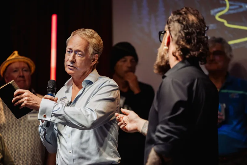 A community presenter gestures toward the host while explaining his project.