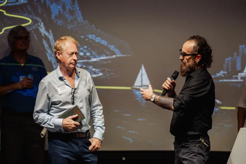 The host gestures toward the community presenter while speaking.