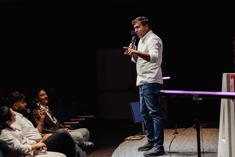 Taleeb Noormohamed speaks at the edge of the stage to the front rows.