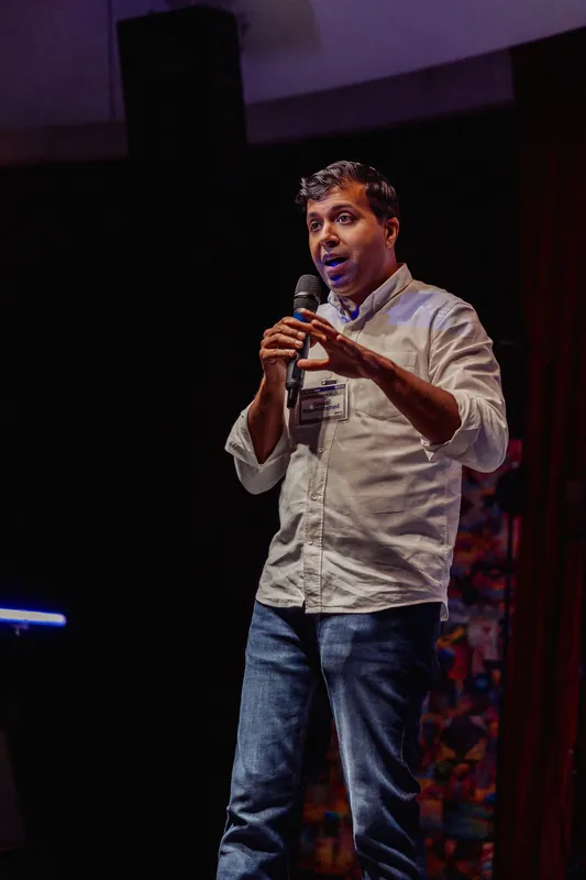 Taleeb Noormohamed brings both hands together around the microphone.