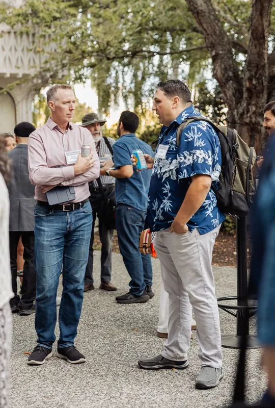 Attendees chat over drinks beneath the trees at the reception.