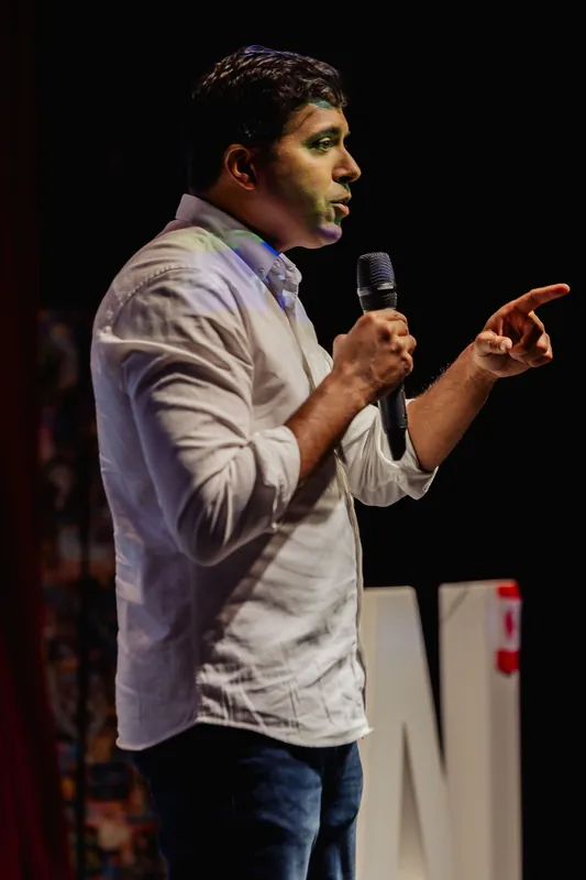Taleeb Noormohamed points lightly while speaking from the stage.