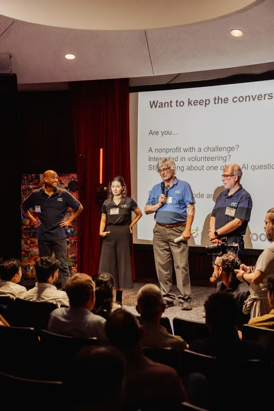 Community presenters gather onstage beneath a slide inviting people to continue the conversation.