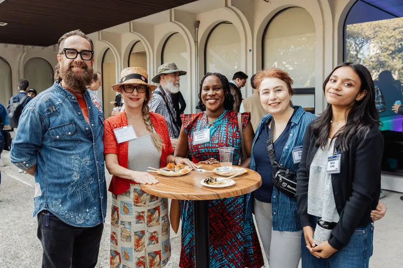 Five attendees gather for a cheerful group portrait around a patio table.