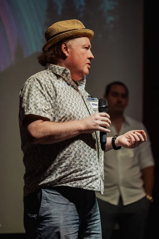 A presenter in a straw hat continues his onstage announcement.