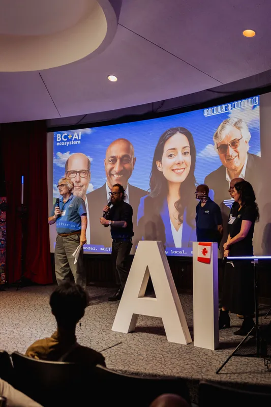 The Data for Good Vancouver team stands beneath a projected collage of team portraits.