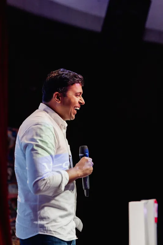 Taleeb Noormohamed speaks in profile from the front of the stage.